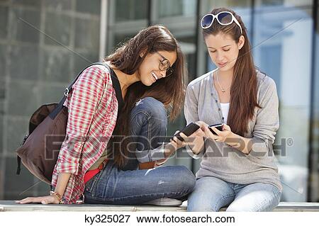 Two young female friends reading messages View Large Photo Image Stock Photo - Two young female friends reading messages. Fotosearch