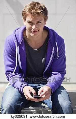 Young man text messaging on a mobile phone View Large Photo Image Stock Image - Young man text messaging on a mobile phone. Fotosearch