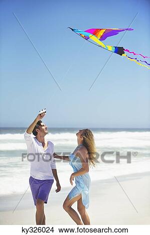 Couple flying kite on the beach View Large Photo Image Picture - Couple flying kite on the beach. Fotosearch