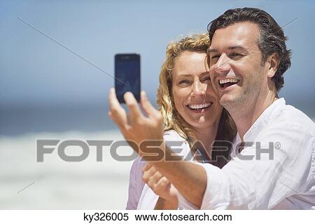 Couple taking a picture of themselves with a mobile phone View Large Photo Image Stock Photography - Couple taking a picture of themselves with a mobile phone. Fotosearch