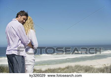 Man embracing a woman from behind on the beach View Large Photo Image Stock Photo - Man embracing a woman from behind on the beach. Fotosearch