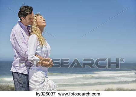 Stock Photo - Man embracing a woman from behind. Fotosearch