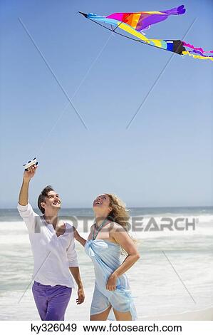 Mid adult couple flying kite on the beach View Large Photo Image Stock Photo - Mid adult couple flying kite on the beach. Fotosearch
