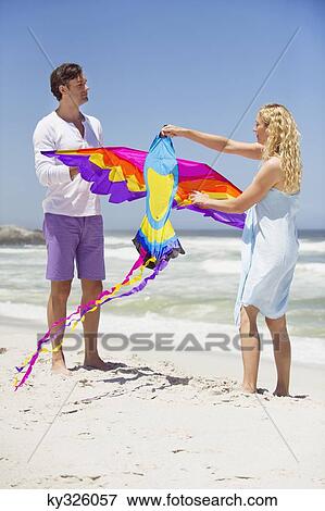 Mid adult couple holding animal shaped kite on the beach View Large Photo Image Stock Photo - Mid adult couple holding animal shaped kite on the beach. Fotosearch