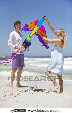 Mid adult couple holding animal shaped kite on the beach View Large Photo Image Stock Photograph - Mid adult couple holding animal shaped kite on the beach. Fotosearch