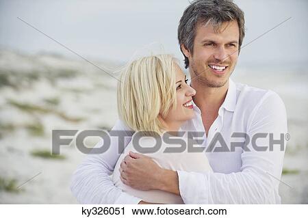 Mid adult man embracing his wife and smiling View Large Photo Image Stock Image - Mid adult man embracing his wife and smiling. Fotosearch