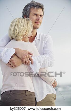 Mid adult man embracing his wife View Large Photo Image Stock Photo - Mid adult man embracing his wife. Fotosearch