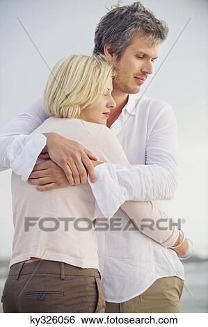 Mid adult man embracing his wife View Large Photo Image Stock Photograph - Mid adult man embracing his wife. Fotosearch