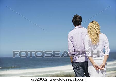Rear view of a couple looking at sea View Large Photo Image Stock Image - Rear view of a couple looking at sea. Fotosearch