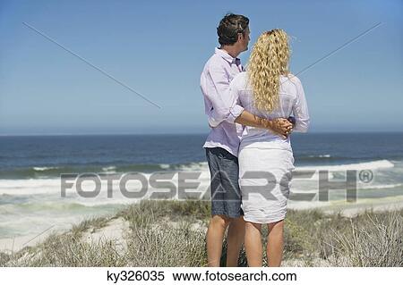 Rear view of a couple looking at sea View Large Photo Image Stock Photography - Rear view of a couple looking at sea. Fotosearch