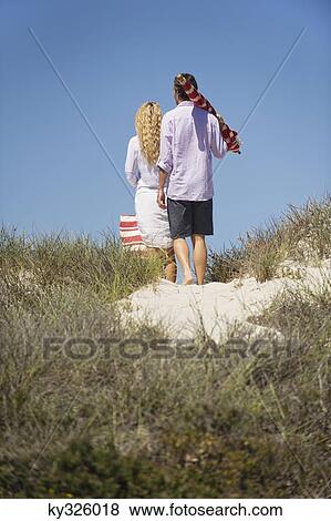 Stock Photo - Rear view of a couple walking on the beach. Fotosearch