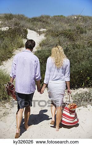 Stock Photograph - Rear view of a couple walking on the beach. Fotosearch