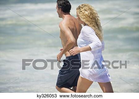 Side profile of a couple running on the beach View Large Photo Image Stock Image - Side profile of a couple running on the beach. Fotosearch