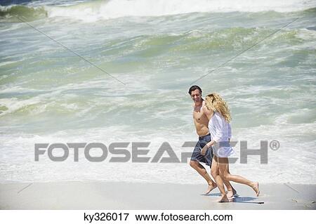 Side profile of a couple running on the beach View Large Photo Image Stock Photo - Side profile of a couple running on the beach. Fotosearch