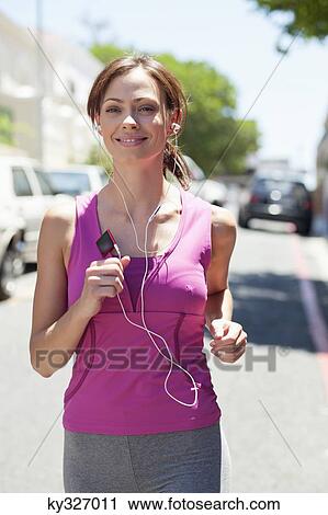 Beautiful young woman listening to mp3 player while jogging View Large Photo Image Stock Image - Beautiful young woman listening to mp3 player while jogging. Fotosearch