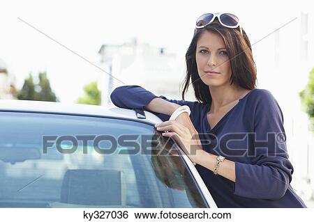 Stock Photograph - Portrait of a beautiful woman leaning on a car. Fotosearch
