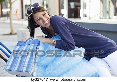 Portrait of a beautiful young woman holding shopping bags View Large Photo Image Stock Photo - Portrait of a beautiful young woman holding shopping bags. Fotosearch
