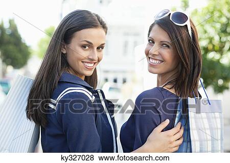 Portrait of two young women standing with shopping bags View Large Photo Image Stock Photo - Portrait of two young women standing with shopping bags. Fotosearch