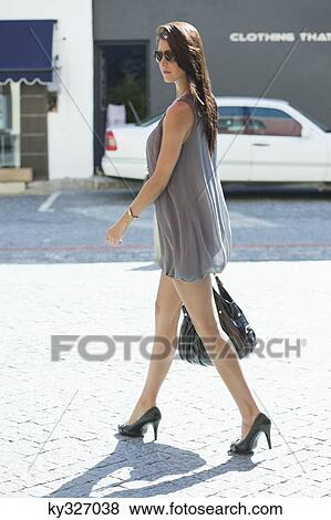 Side profile of a young woman walking View Large Photo Image Stock Photo - Side profile of a young woman walking. Fotosearch