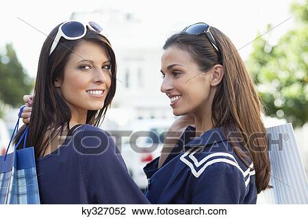 Stock Image - Two young women standing with shopping bags. Fotosearch