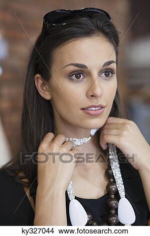 Picture - Young woman trying a necklace in a mall. Fotosearch