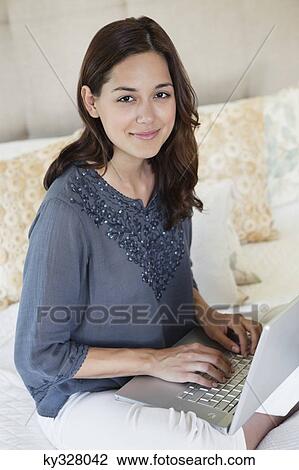 Beautiful young woman using a laptop at home View Large Photo Image Stock Image - Beautiful young woman using a laptop at home. Fotosearch