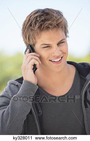 Close-up of a man talking on a mobile phone and smiling View Large Photo Image Stock Image - Close-up of a man talking on a mobile phone and smiling. Fotosearch