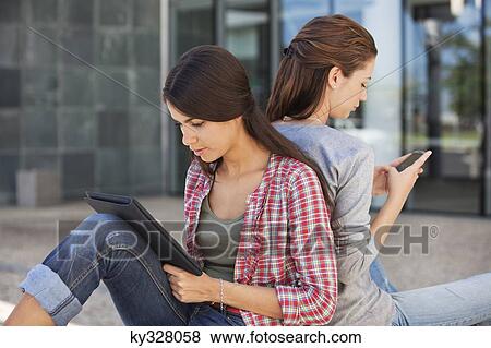 Female friends holding file and mobile phone View Large Photo Image Stock Photo - Female friends holding file and mobile phone. Fotosearch