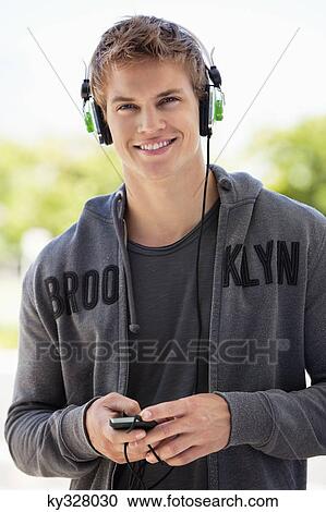 Stock Image - Man listening to music with headphones and smiling. Fotosearch