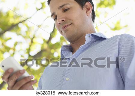 Mid adult man using a mobile phone View Large Photo Image Stock Photography - Mid adult man using a mobile phone. Fotosearch