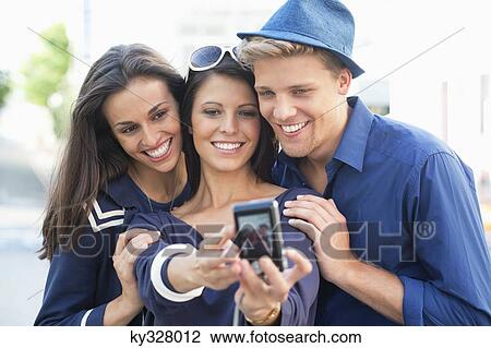 Three young people taking photo of themselves View Large Photo Image Stock Image - Three young people taking photo of themselves. Fotosearch