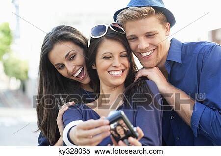 Stock Photography - Three young people taking photo of themselves. Fotosearch