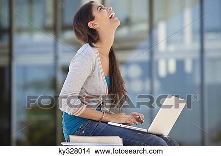 Picture - Woman laughing while using a laptop. Fotosearch