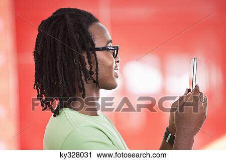 Stock Image - Young man taking a picture of himself with a mobile phone. Fotosearch