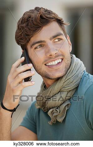 Young man talking on a mobile phone View Large Photo Image Stock Photograph - Young man talking on a mobile phone. Fotosearch