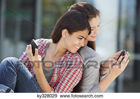 Young woman showing her message to her friend View Large Photo Image Stock Photo - Young woman showing her message to her friend. Fotosearch