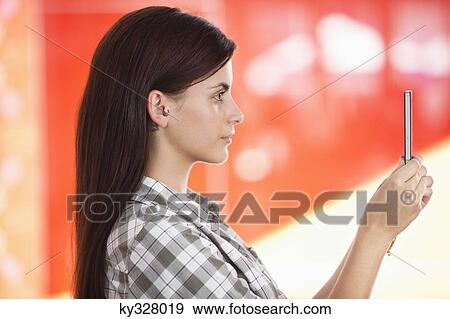 Young woman taking a picture of herself with a mobile phone View Large Photo Image Stock Photo - Young woman taking a picture of herself with a mobile phone. Fotosearch