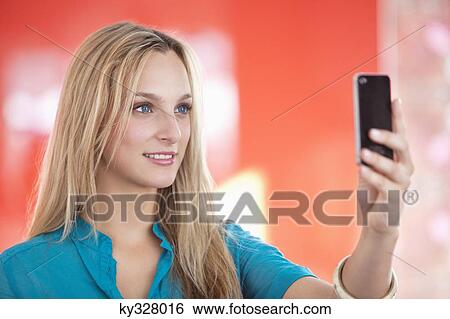 Stock Photograph - Young woman taking a picture of herself with a mobile phone. Fotosearch