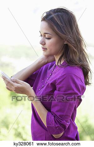 Young woman using a mobile phone with hand in hair View Large Photo Image Stock Image - Young woman using a mobile phone with hand in hair. Fotosearch