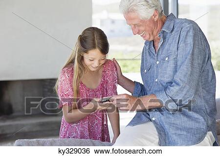 Man showing a message from a mobile phone to his granddaughter View Large Photo Image Stock Photograph - Man showing a message from a mobile phone to his granddaughter. Fotosearch