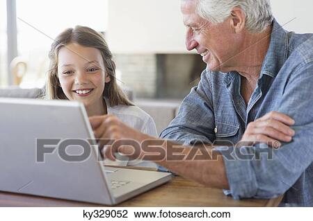 Man showing laptop to his granddaughter and smiling View Large Photo Image Stock Image - Man showing laptop to his granddaughter and smiling. Fotosearch