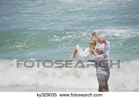 Senior couple lifting their granddaughter in air on the beach View Large Photo Image Stock Photography - Senior couple lifting their granddaughter in air on the beach. Fotosearch