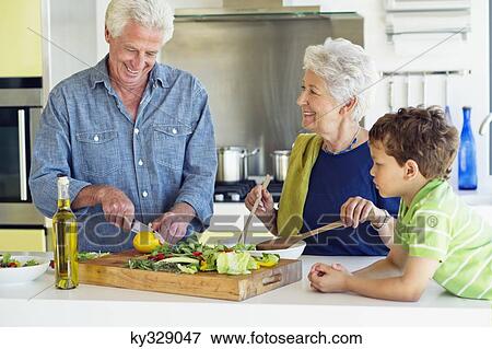 Senior couple preparing food with grandson lying on kitchen counter at house View Large Photo Image Stock Photo - Senior couple preparing food with grandson lying on kitchen counter at house. Fotosearch
