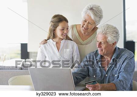 Senior man doing home shopping with a credit card with his family near him View Large Photo Image Stock Image - Senior man doing home shopping with a credit card with his family near him. Fotosearch