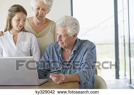 Senior man doing home shopping with a credit card with his family near him View Large Photo Image Stock Image - Senior man doing home shopping with a credit card with his family near him. Fotosearch