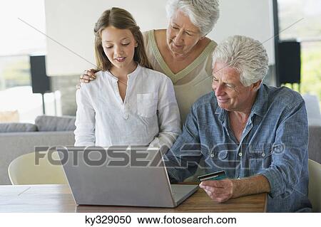 Senior man doing home shopping with a credit card with his family near him View Large Photo Image Stock Image - Senior man doing home shopping with a credit card with his family near him. Fotosearch