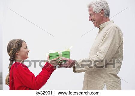 Senior man giving gift to his granddaughter View Large Photo Image Stock Image - Senior man giving gift to his granddaughter. Fotosearch