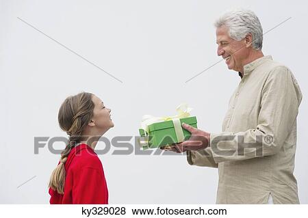 Senior man giving gift to his granddaughter View Large Photo Image Stock Photo - Senior man giving gift to his granddaughter. Fotosearch