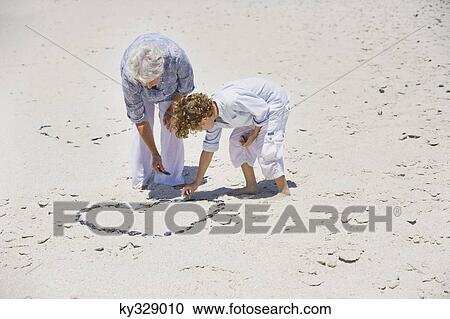Senior woman and her grandson making a heart shape on the beach View Large Photo Image Stock Image - Senior woman and her grandson making a heart shape on the beach. Fotosearch