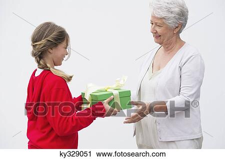 Senior woman giving gift to her granddaughter View Large Photo Image Stock Image - Senior woman giving gift to her granddaughter. Fotosearch
